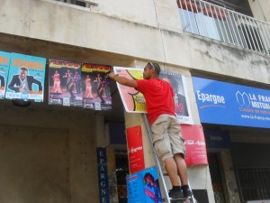 Un afficheur sur une échelle pose des affiches au festival d'Avignon 2015 pour les spectacles de JeanFi, Luis De La Carrasca, King Kong Théorie